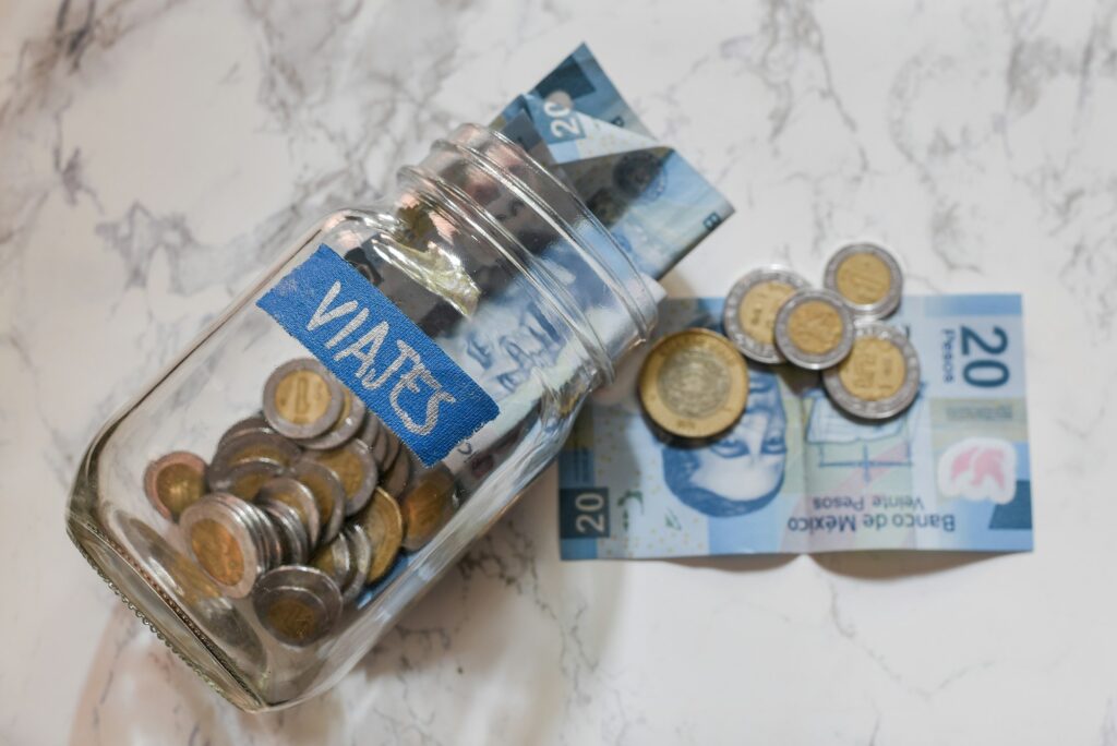 High angle view of pesos and coins in a jar with a [Viajes - travels] sticker on it on the table